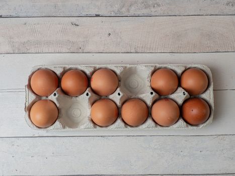 eggs in their box on white wooden background