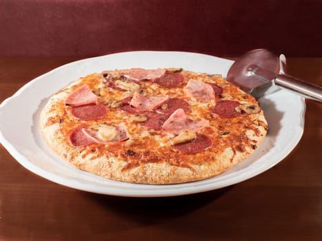 homemade pizza on white plate and wooden background overhead view