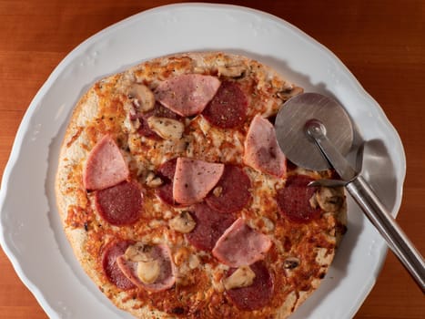 homemade pizza on white plate and wooden background overhead view