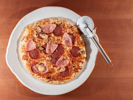 homemade pizza on white plate and wooden background overhead view