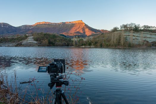 mountains at sunrise with reflection in the lake and camera in the foreground