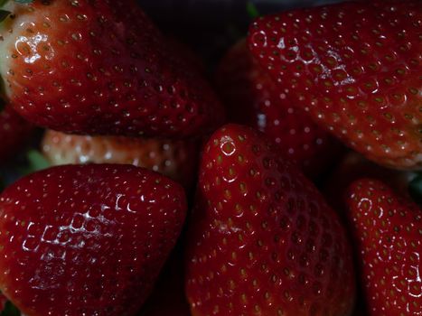 several dark strawberries macro photo