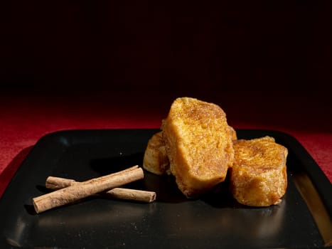 three french toast with cinnamon on black plate and dark background