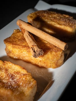 three french toast with cinnamon on white plate and dark background