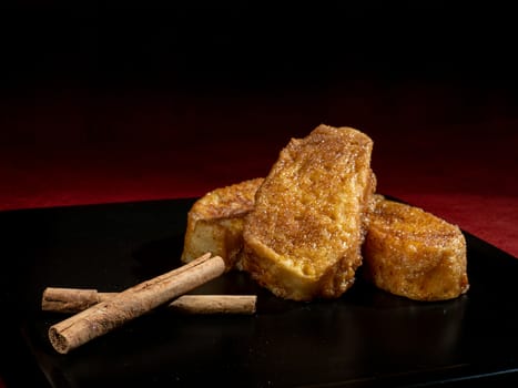 three french toast with cinnamon on black plate and dark background