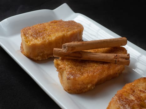 three french toast with cinnamon on white plate and dark background