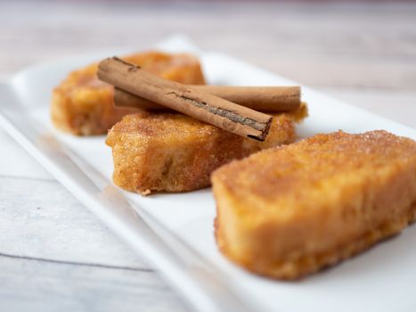 three french toast with cinnamon on white plate and light background