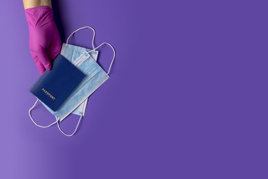 Doctor holds passports and respiratory surgical face mask in hands pink medical glove on violet background. Pandemic corona virus, insurance, airborne diseases, SARS, grippe