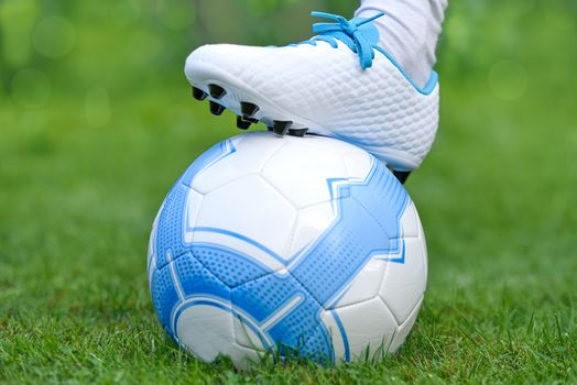 Close-up of little boy leg playing football on football pitch.