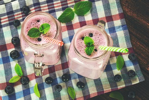 Blueberrie smoothie made with fresh organic blueberries, mint and  yogurt in vintage jars on a wooden table (reduced tone)