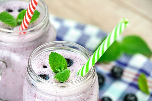 Top view of a blueberry smoothie made with fresh organic blueberries, mint and yogurt in vintage jar on a wooden table.