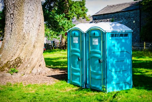 Two blue - white portable toilet cabins at outside event