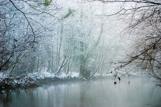 Scenic view of a river in winter. Dense fog over the river in winter. Sunrise in the thick winter fog