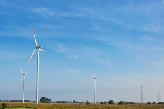 Beautiful rural landscape with ecological wind farms on the blue sky background