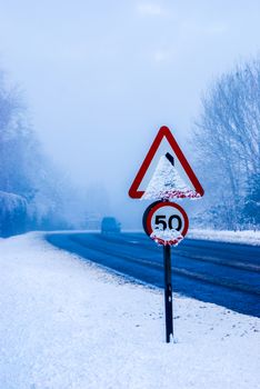 Snowy road with traffic sign and heavy snowfall on a country road.