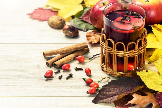 Concept of seasonal warm tea with wild rose, spices, lemons and surrounded by autumn rustic decoration (vintage effect).