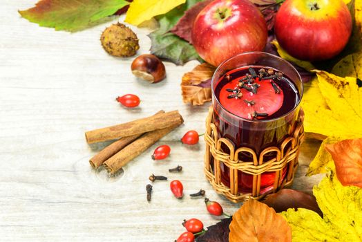 Concept of seasonal warm tea with wild rose, spices, lemons and surrounded by autumn rustic decoration.