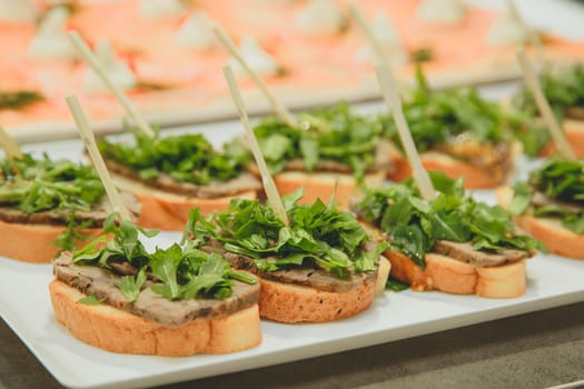 a plate of sandwiches and stuffing on a toothpick baguette, beef and lettuce.