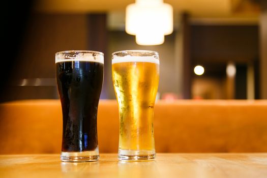 Two glasses of beer over a dark background