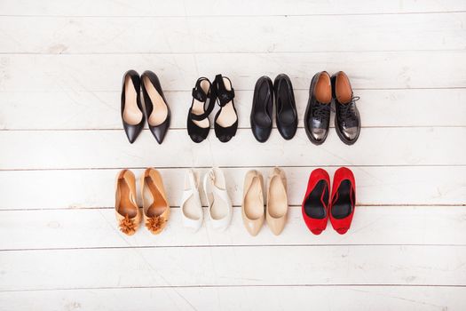 Different summer women's shoes on a wooden white floor. view from above