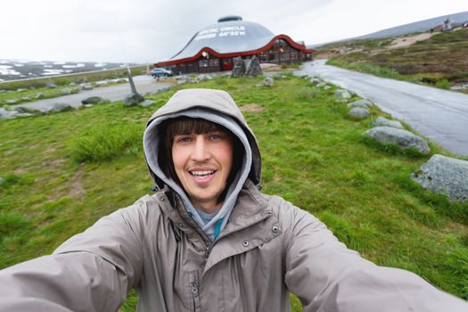Tourist man making selfie Arctic circle center. Landmark on Lofoten islands. Norway.