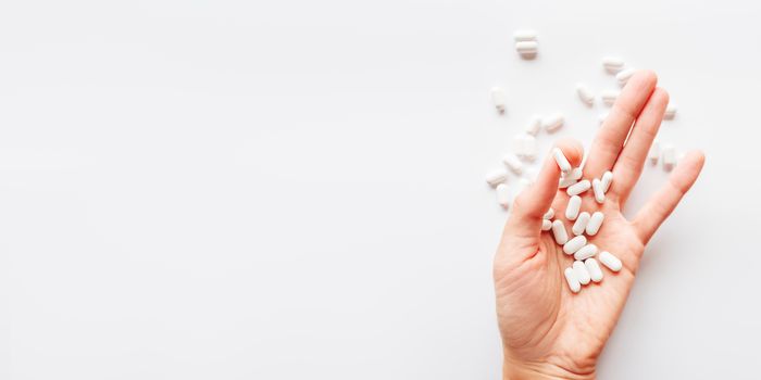 Palm hand full of white scattering pills. Capsules with medicines on light background. Flat lay, top view.