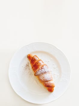 Continental breakfast background - croissant on plate. White table with copy space. Top view.