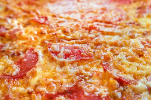Close up photo of pizza. Macro photo of baked pizza ingredients - cheese with ham and tomatoes. Traditional italian cuisine.