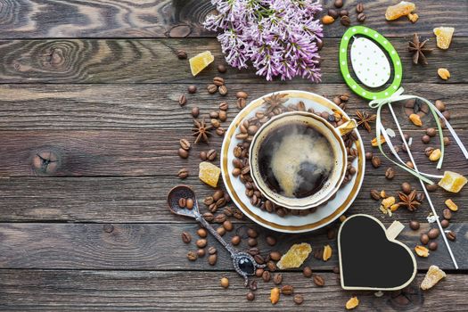 Rustic wooden background with cup of coffee and Easter decorations. Hot beverage with heart chalkboard. Top view, place for text.