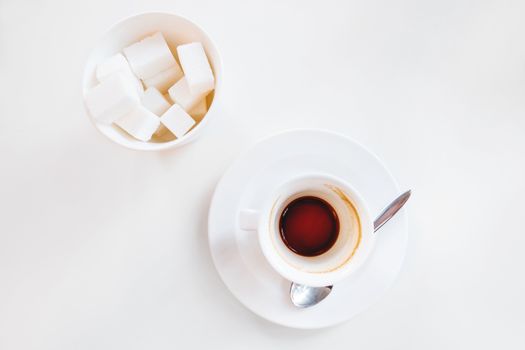 Empty coffee cup and glass with sugar on white background. End of coffee break. Coffee grinds in white mug.