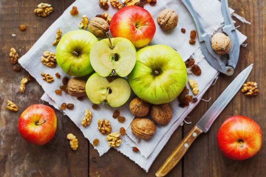 Healthy snack background - fruits and nuts. Green and red apples, raisins and walnuts on rustic wooden background.