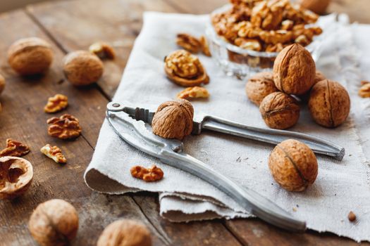 Glass bowl with walnuts on rustic homespun napkin. Healthy snack on old wooden background.