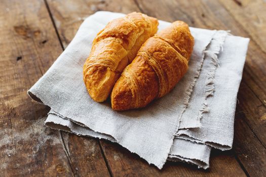 Breakfast background - pair of croissants on rustic wooden background.