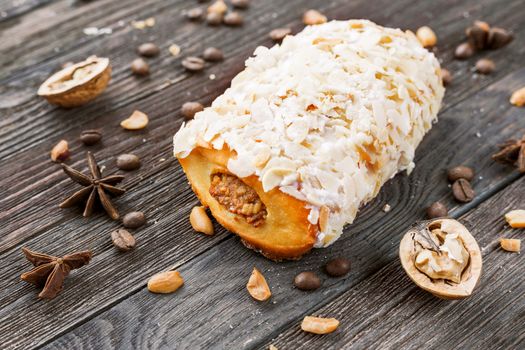 Bun with marzipan on rustic wooden background. Different spices around peanut dessert - anise stars, coffee beans, walnuts.