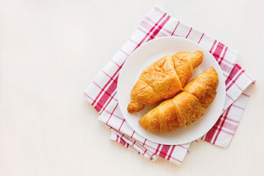 Tasty continental breakfast background - pair of croissants on plaid red napkin. Place for text, top view.