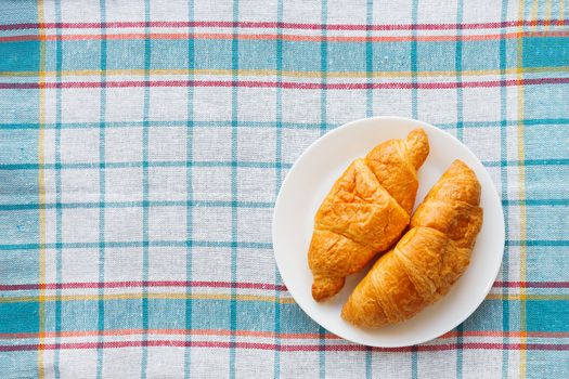 Continental breakfast background - pair of croissants on plaid blue napkin. Rustic background with place for text. Top view.