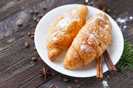 Continental breakfast background - pair of croissants with cinnamon. Rustic wooden background.