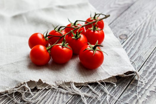 Cherry tomatoes on a wooden surface and homespun cloth with natural light.