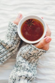 Women holds a cup of hot tea with anise star. Cozy morning at home.