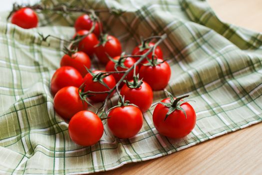 Cherry tomatoes on a wooden surface and cloth with natural light.