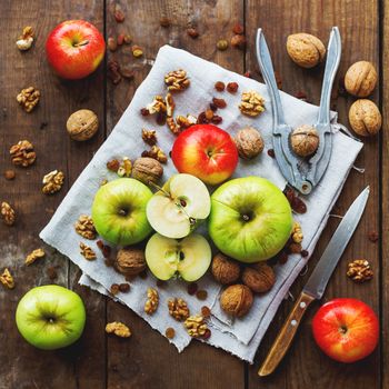 Healthy snack background - fruits and nuts. Green and red apples, raisins and walnuts on rustic wooden background.