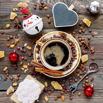 Rustic wooden background with cup of coffee and New Year decorations. Heart shaped chalkboard. Christmas beverage with ginger and anise. Top view, place for text.