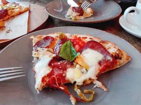 Piece of fresh hot pizza with cheese, jalapenos pepper, tomatoes and basil. Tasty italian food.