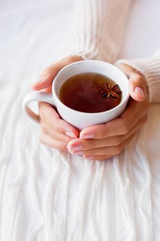 Women holds a cup of tea with anise star. Cozy morning at home.