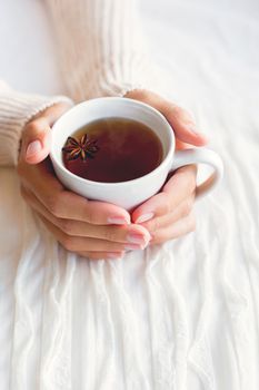 Women holds a cup of tea with anise star. Cozy morning at home.