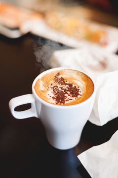 Cup of coffee with cinnamon. Hot tasty cappucino in white mug.