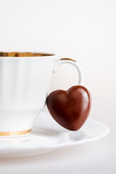 White old fashioned porcelain cup and chocolate candy in shape of heart.