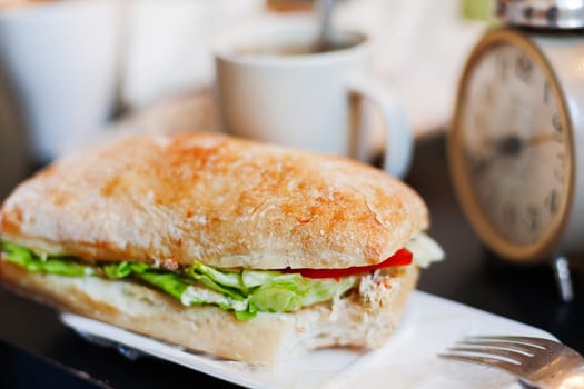 Tme for lunch with big tasty sandwich and cup of coffee.