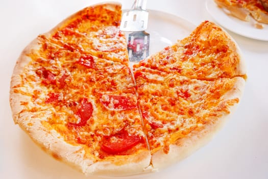 Pizza with baked ingredients - cheese with ham and tomatoes. Traditional italian cuisine.