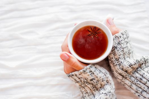 Women holds a cup of hot tea with anise star. Cozy morning at home.